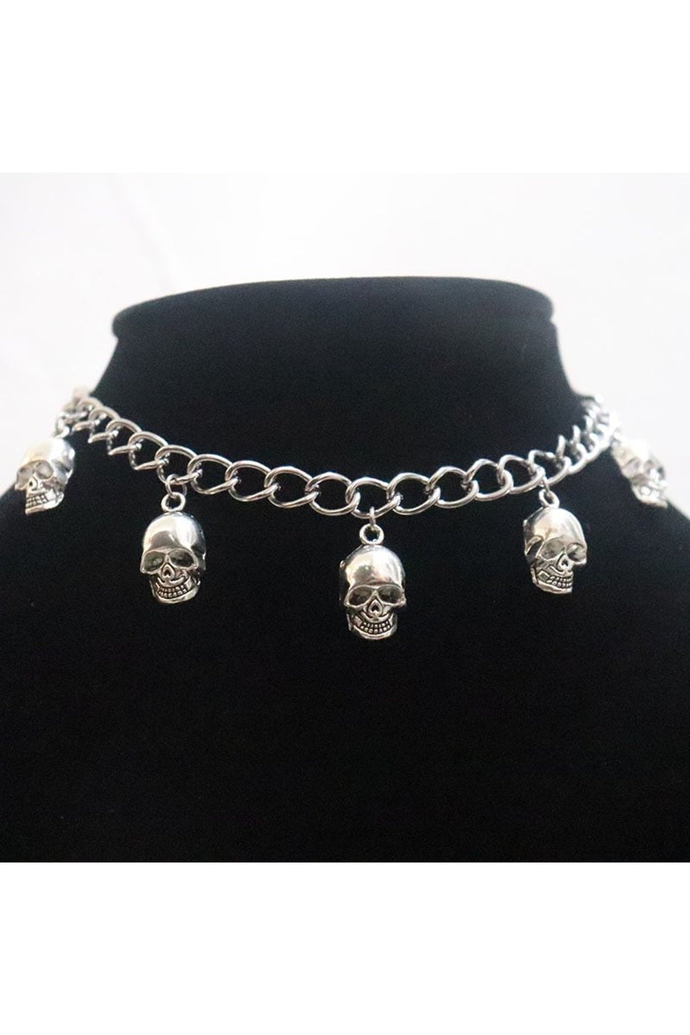 Gotik tarzda metal kolye, kuru kafayı yansıtıyor.