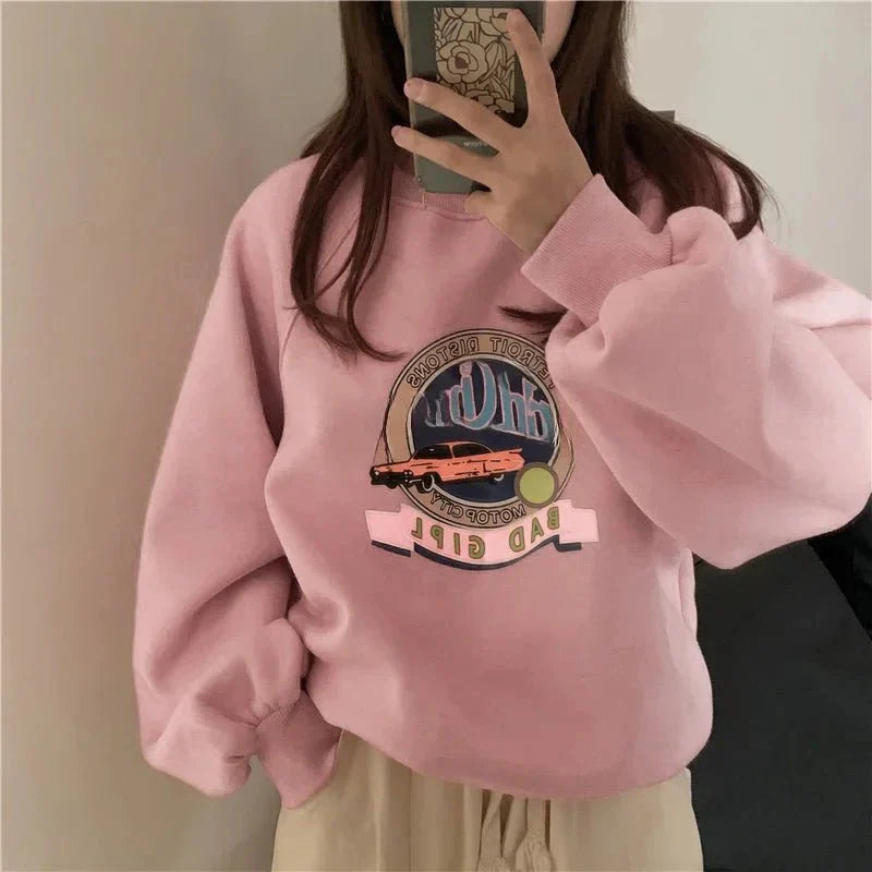 Pastel pembe tonlarındaki grafik desenli sweatshirt şıklığıyla öne çıkıyor.